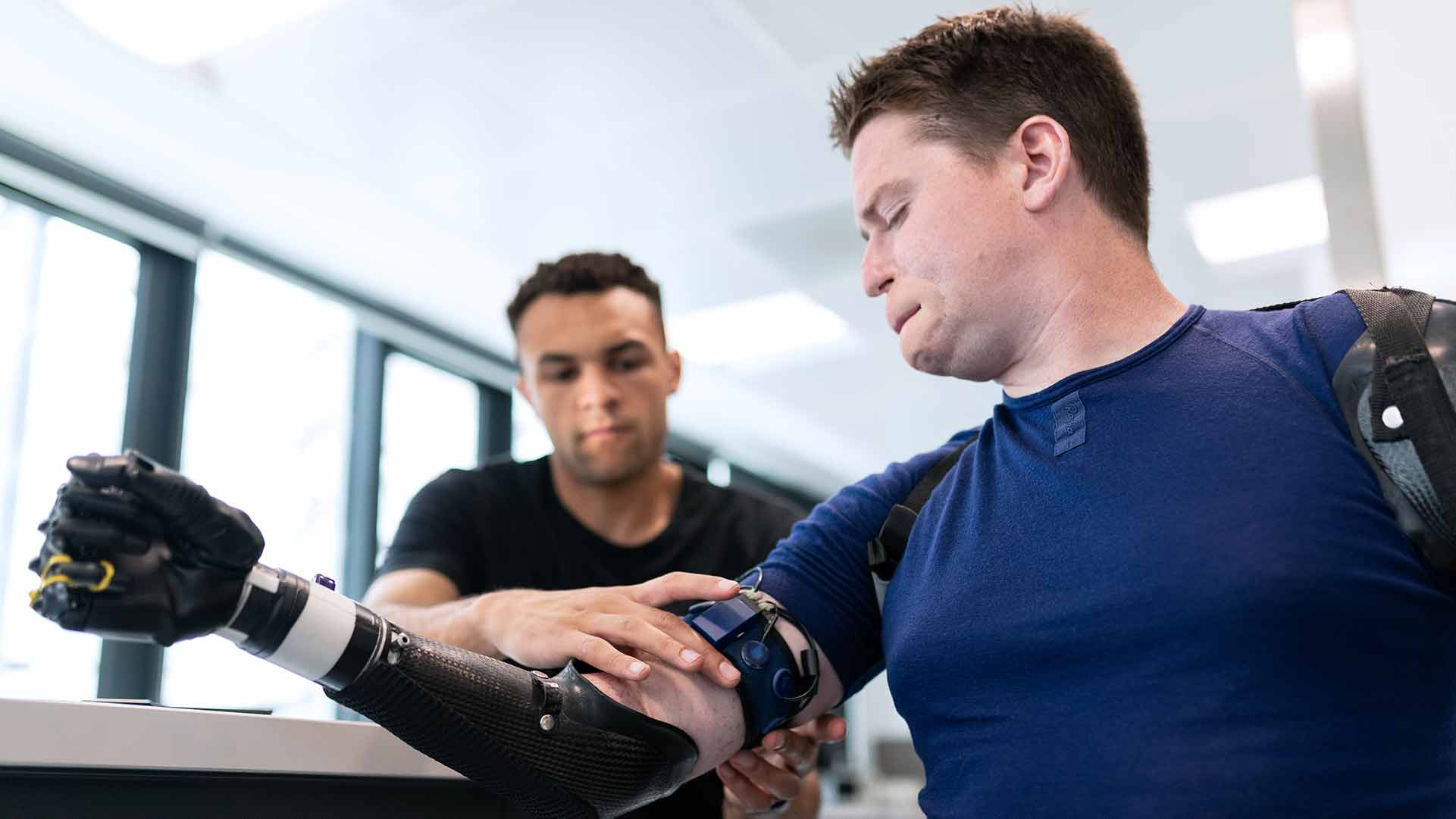 man sitting while technician works on his prosthetic arm